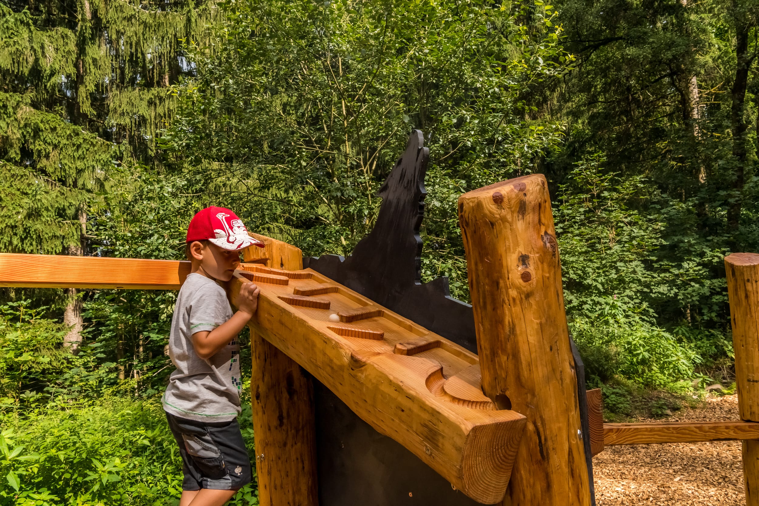 Auf dem Wolfspfad ein Kind spielt an einer Murmelbahn